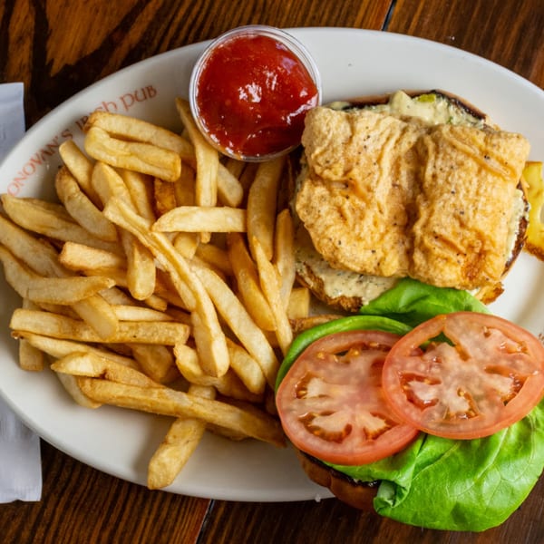 O'Donovan's Irish Pub fish sandwich with lettuce, tomato, fries, and ketchup on a white plate.
